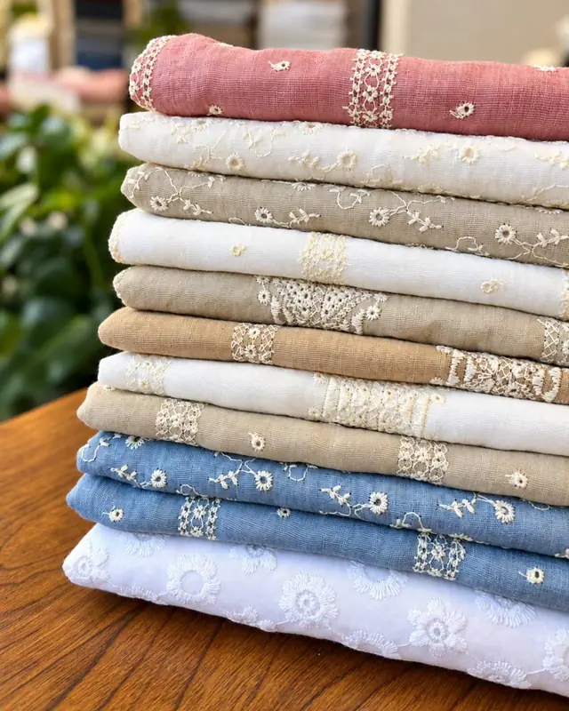 Pila de linos bordados en rosa, crudo, beige, celeste y broderie blanca
